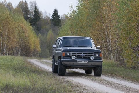 1987 Ford Bronco - This 1987 Ford Bronco navigates a winding dirt road through autumn foliage.