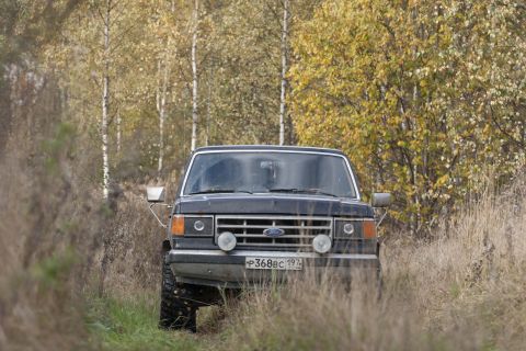 1987 Ford Bronco - A 1987 Ford Bronco navigates a grassy, wooded path during autumn.