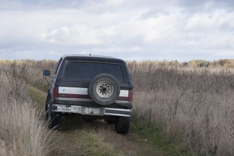 1987 Ford Bronco - 1987 Ford Bronco on a dirt road in a grassy field under a cloudy sky.