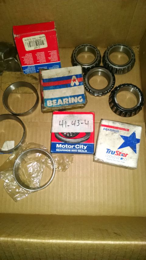 1994 Ford Bronco - Various wheel bearings and seals are laid out in a cardboard box, with some parts in original packaging.
