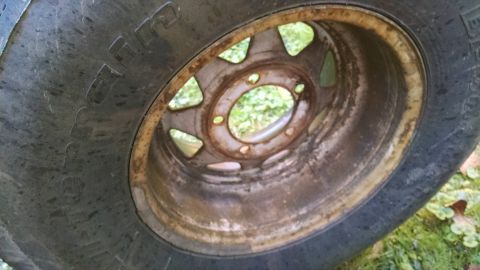 1994 Ford Bronco - A close-up view of a rusty wheel and tire, showing the texture of the tire and the corroded rim.