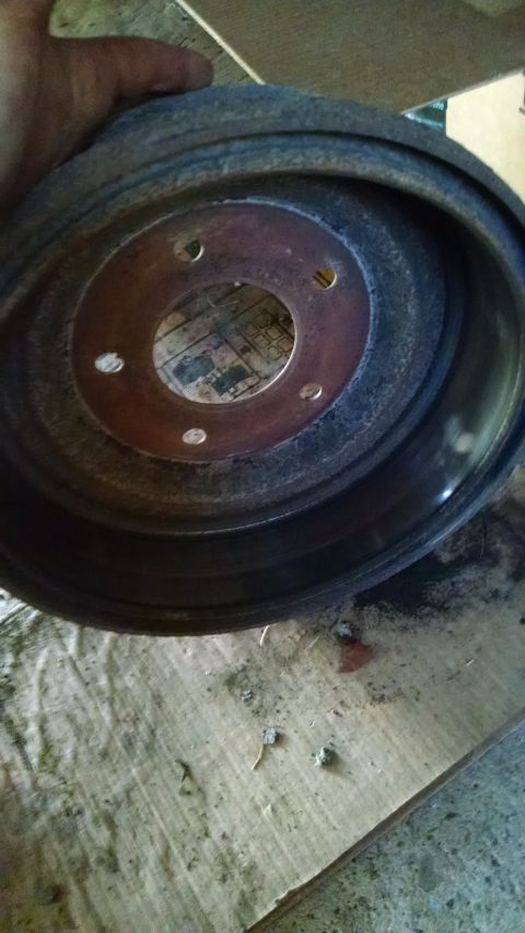 1994 Ford Bronco - A rusty brake drum is held up for inspection, with a website logo visible in the corner.