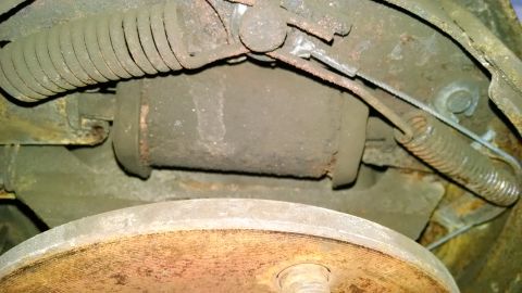 1994 Ford Bronco - Close-up view of a drum brake assembly, showing springs and a brake cylinder.