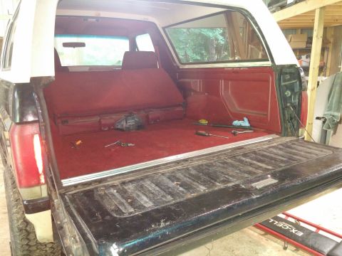 1989 Ford Bronco - The interior of a 1989 Ford Bronco is shown with the tailgate down, revealing red carpeting and seats.