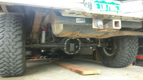 1996 Ford Bronco - The rear underside of a lifted Ford Bronco shows large off-road tires, a differential, and a trailer hitch. A license plate with the text "…
