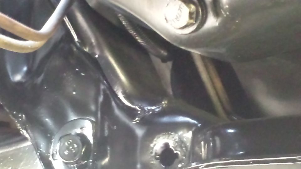 Close-up of black painted vehicle frame with bolts and suspension parts visible