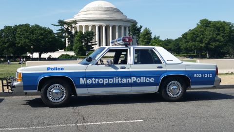 2001 Ford Crown Victoria - A side view of a police car parked near a domed building.