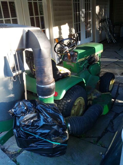 1982 Kubota RTV900 - John Deere lawn tractor with a bagger attachment and hose connected.