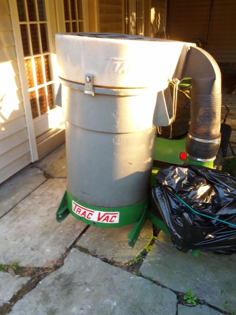 1982 Kubota RTV900 - A Trac Vac leaf vacuum unit is shown with a collection bag, positioned outdoors on a patio.