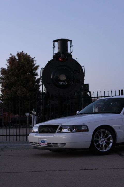 2000 Mercury Grand Marquis - A white sedan is parked in front of a vintage steam locomotive at dusk.