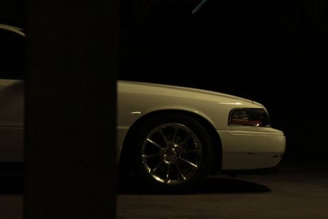 2000 Mercury Grand Marquis - A white sedan is partially obscured by a dark column, showing its front wheel and fender.