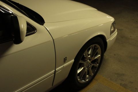 2000 Mercury Grand Marquis - Front quarter panel and wheel of a white 2000 Mercury Grand Marquis.