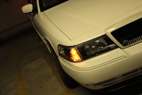 2000 Mercury Grand Marquis - A white 2000 Mercury Grand Marquis is viewed from a 3/4 front angle, highlighting its grille and headlight assembly.