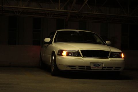 2000 Mercury Grand Marquis - A white 2000 Mercury Grand Marquis is parked indoors, showing its front grille and headlights.