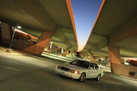 2000 Mercury Grand Marquis - A white 2000 Mercury Grand Marquis is captured in a three-quarter front view under a concrete overpass as the sky transitions to twilight.