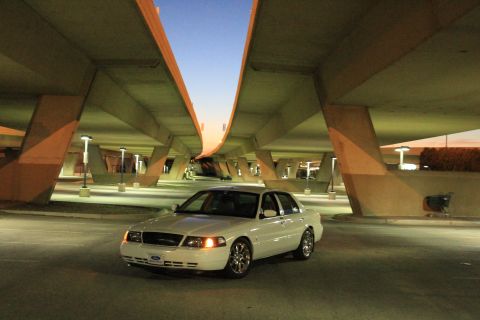 2000 Mercury Grand Marquis - A white 2000 Mercury Grand Marquis is parked beneath a concrete overpass as the sky transitions to dusk.