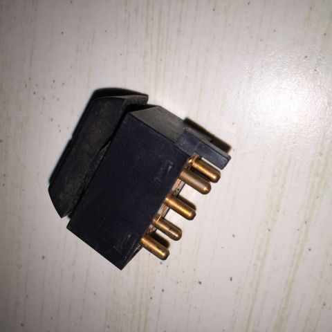 1989 Ford Bronco - Close-up of a black plastic window lock switch with multiple gold-colored pins.