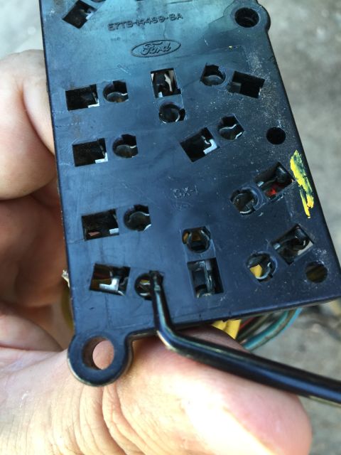 1989 Ford Bronco - A Ford window switch assembly is shown, with a tool being used to manipulate one of the electrical connectors.