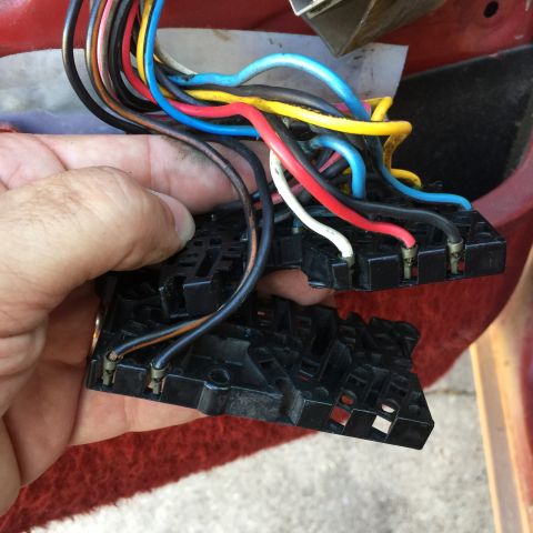 1989 Ford Bronco - A hand holds a damaged electrical connector with a bundle of wires, likely for a vehicle's door lock or window controls.