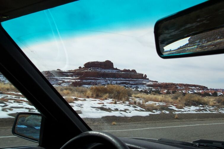 Interior view of a vehicle with a snowy desert landscape visible through the windshield and side mirror