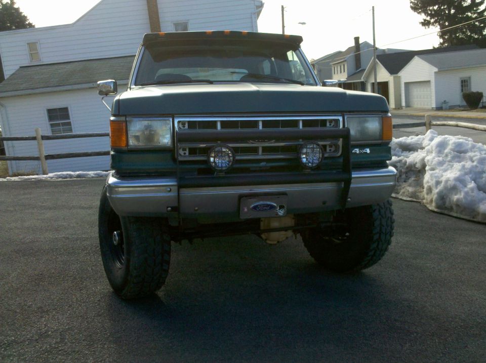 Green 1990 Ford Bronco front view, with aftermarket grille guard and lights