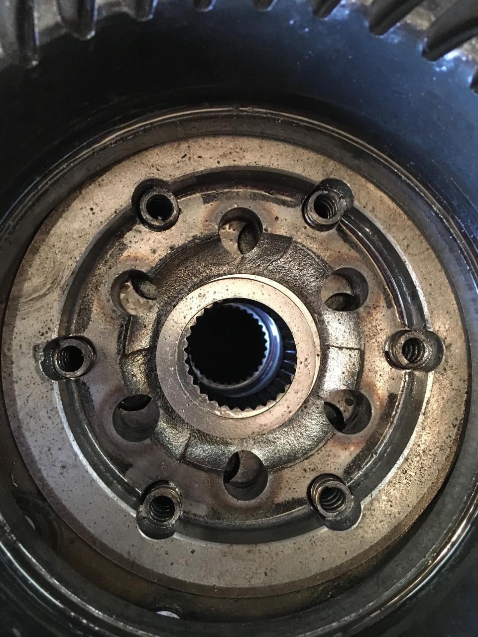 Close-up of a differential gear with splines in the center and bolt holes around the perimeter