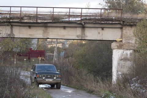 1987 Ford Bronco - A black 1987 Ford Bronco is parked on a muddy road beneath an overpass.