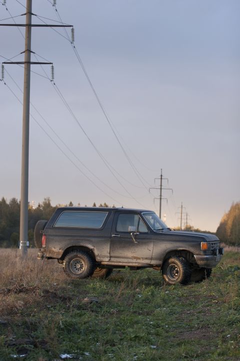 1987 Ford Bronco - A 1987 Ford Bronco is seen parked in a field with power lines overhead.