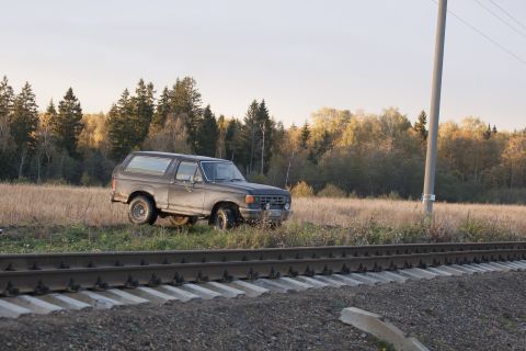 1987 Ford Bronco - 1987 Ford Bronco parked in a field next to railroad tracks during autumn.