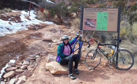 1990 Ford Bronco - A woman poses with her bicycles next to an informational sign at Canyonlands National Park.