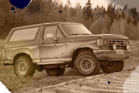 1987 Ford Bronco - 1987 Ford Bronco in a dirt lot, showing its side profile.