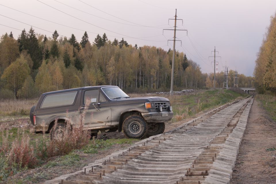 Pickup truck parked on a dirt road next to trees with fall colors
