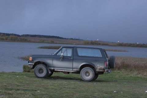 1987 Ford Bronco - This 1987 Ford Bronco is parked on grassy terrain next to a body of water.