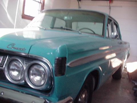 1964 Mercury Comet - A teal 1964 Mercury Comet sedan is parked indoors, showing its distinctive front grille and side trim.