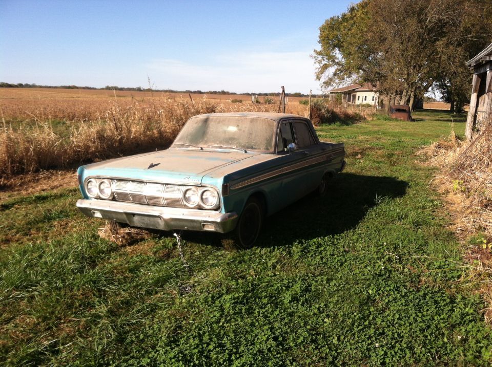 Dusty blue 1961 Mercury Comet sedan parked in a grassy field next to a cornfield
