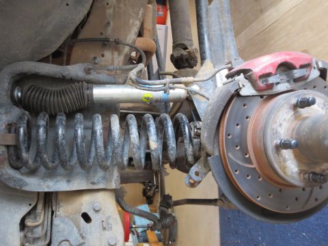 1996 Ford Bronco - Close-up view of a vehicle's rear suspension system, showing a shock absorber, coil spring, and brake assembly.