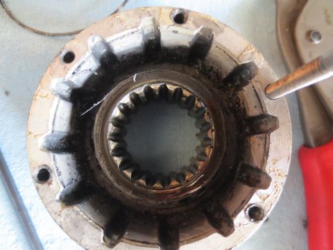 1996 Ford Bronco - A close-up view of a dirty, splined automotive part with a bolt being inserted.