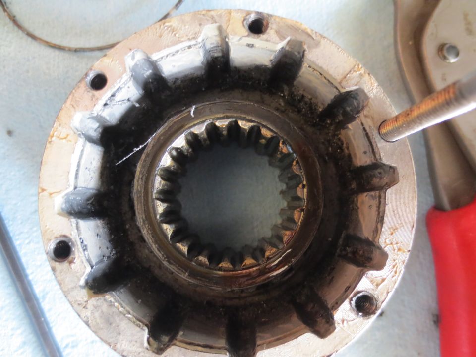 Close-up of a dirty, splined metal automotive part with a threaded bolt entering from the right