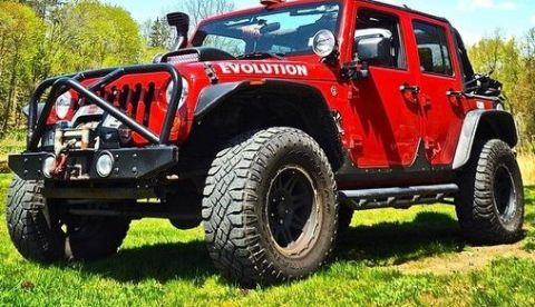 1979 Ford Bronco - This red Jeep Wrangler features off-road modifications and the word 'EVOLUTION' visible on its hood.
