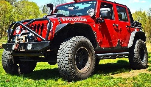 Red Jeep Wrangler with 'EVOLUTION' text and off-road tires