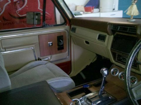1982 Ford Bronco - Interior view of a tan and brown vehicle, wood trim and aftermarket gauges visible on the center console.