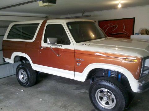 1982 Ford Bronco - This Ford Bronco, likely from the early 1980s, is shown in a garage with a red banner in the background.
