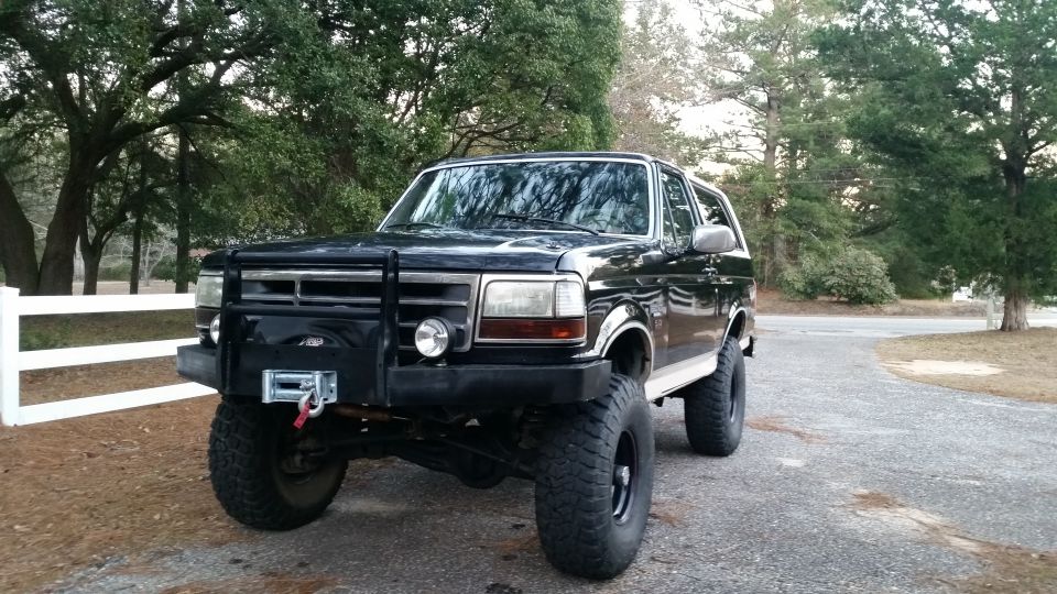 1993 Ford Bronco with aftermarket bumper, winch, and lifted suspension parked outdoors