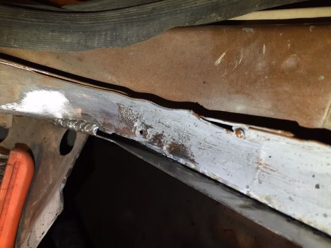1991 Ford Bronco - Close-up view of rusted metal frame showing welds and primer.
