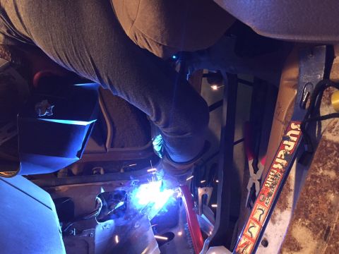 1991 Ford Bronco - A person is welding the rusted floor pan of a vehicle's interior.