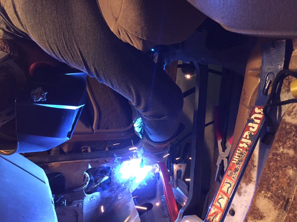 Welder sparks fly as a person repairs the rusted floor pan of a vehicle interior