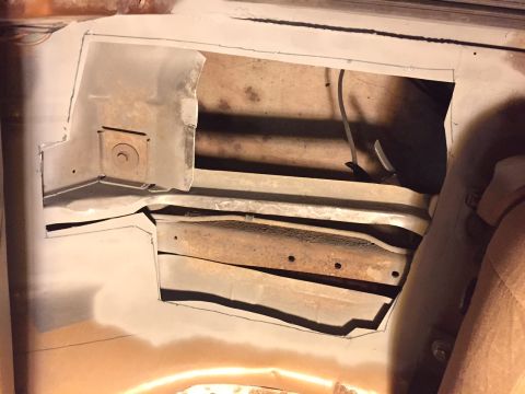 1991 Ford Bronco - Close-up view of a vehicle's corroded floor pan, revealing structural components and wiring beneath.