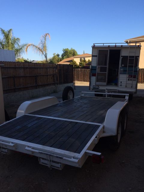 1997 Dodge 3500 - A flatbed trailer is positioned in front of a camper, ready for loading or transport.