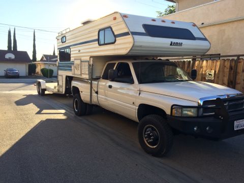 1997 Dodge 3500 - White Dodge 3500 pickup truck equipped with a camper shell and towing a trailer.