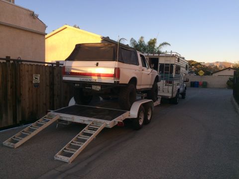 1997 Dodge 3500 - A lifted Ford Bronco is loaded onto a trailer, with a camper behind it.